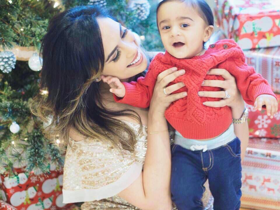 Mom and baby pose for a picture infront of Christmas tree